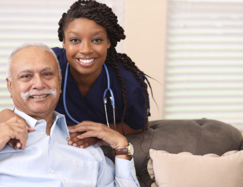 Senior adult, male patient hugs African descent home healthcare nurse.  They have been discussing treatment options in nursing home or home setting.